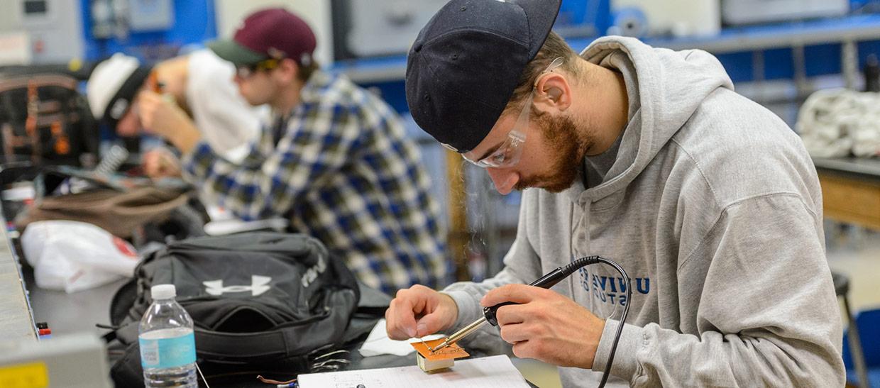 Engineering students working with professor in the classroom